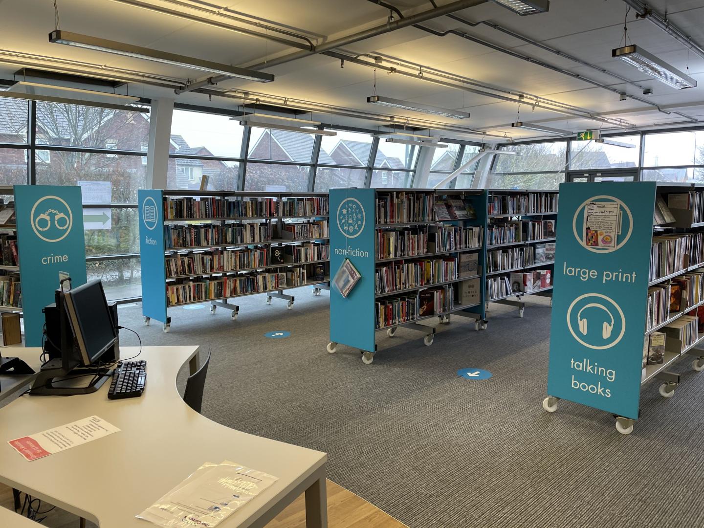 An interior image of the Campus library, with bright blue shelves and books and grey carpet