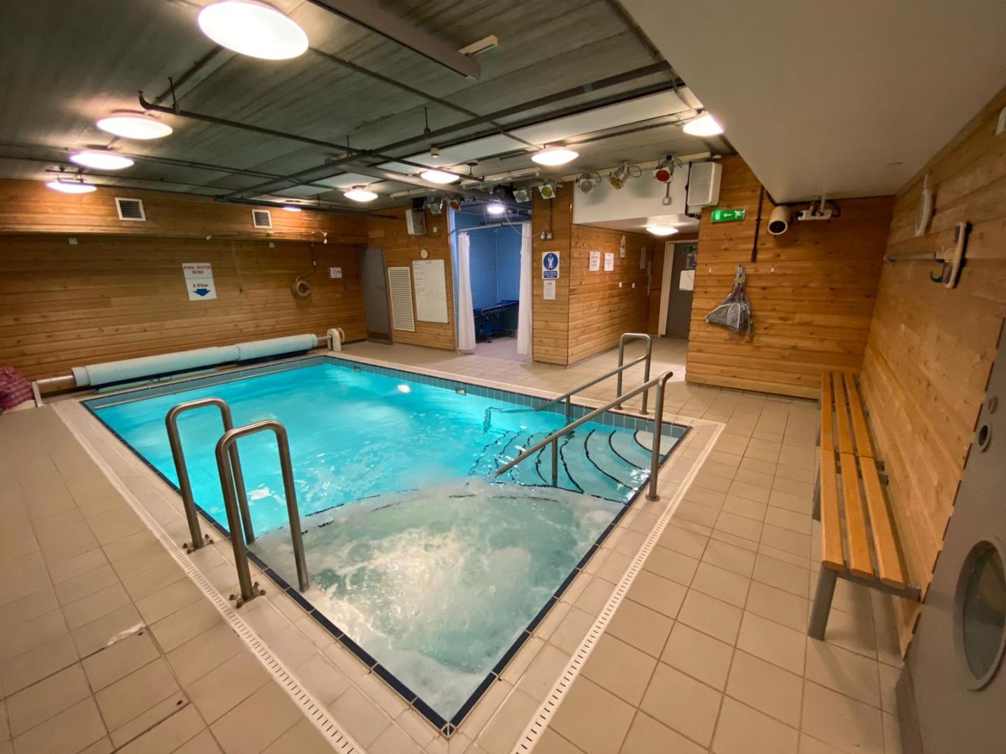 Image of an indoor swimming pool with a bench on the side