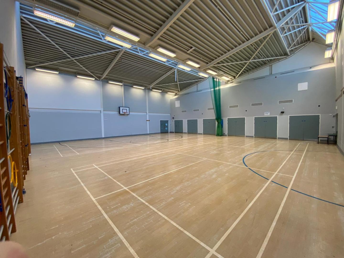 A picture of an indoor  basketball court with wooden floor