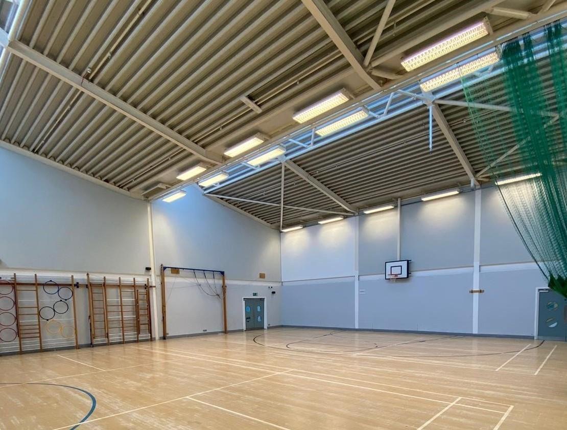 image of an indoor basketball court with wooden floor with rows of hoops running up the side wall