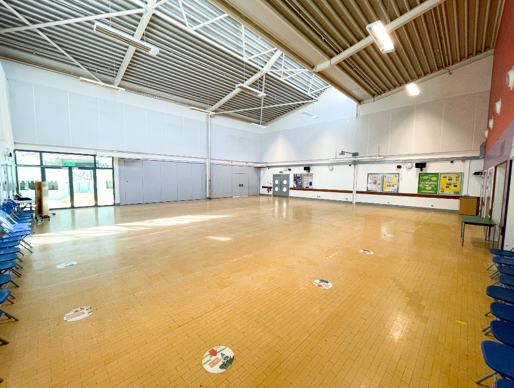 A photograph of the Main Hall room at The Campus - a wide open room with shiny wooden floors and white metal beams in the ceiling. 